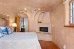 The bedroom has a queen bed that looks onto a gas fireplace embedded within the diamond plaster tree